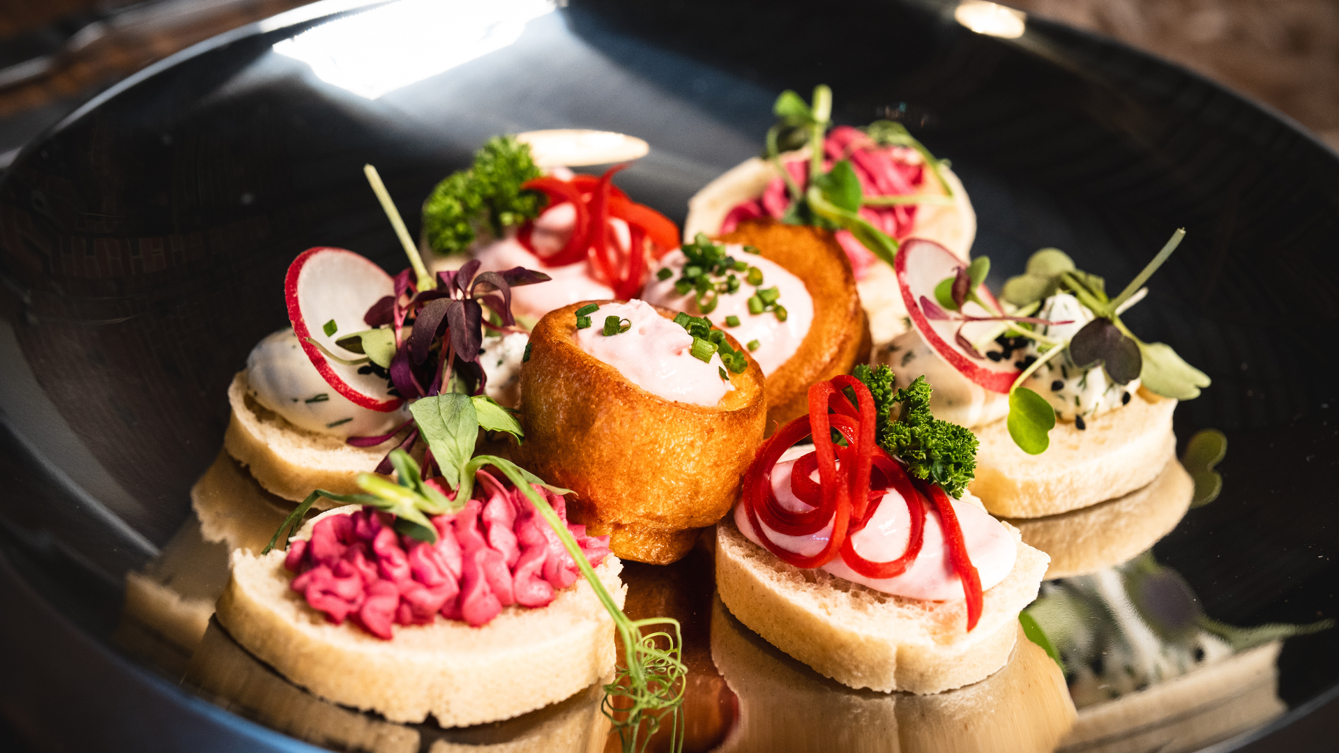 Delicately arranged salmon mousse bites atop crispy pastry shells, garnished with fresh dill, exude elegance on a woven tray.