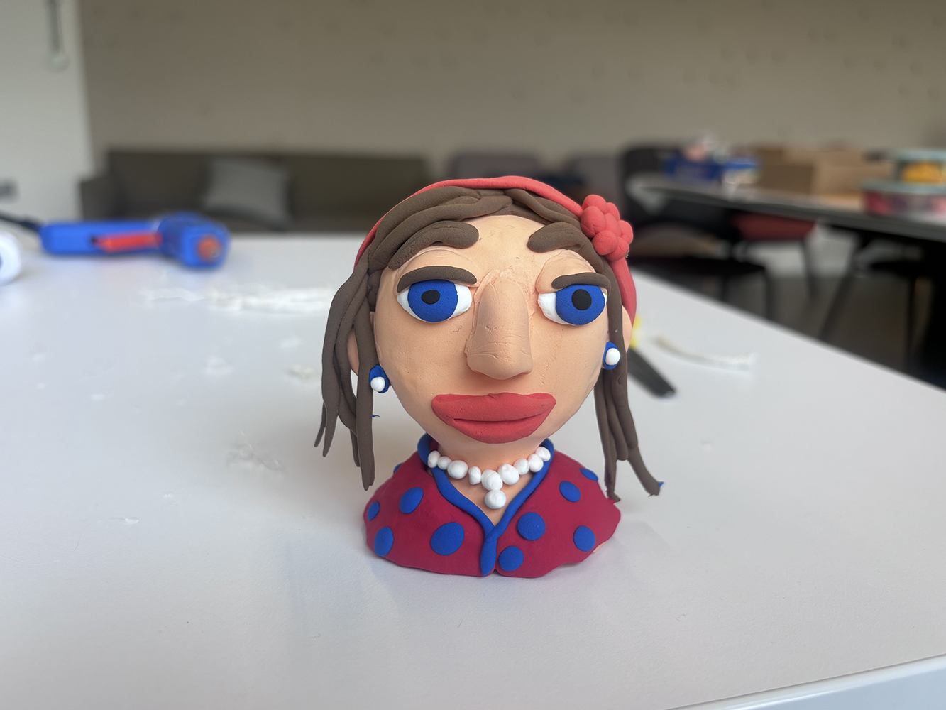 Handmade fondant bust centerpiece in bright red and blue polka dots on a white catering table, with soft indoor daylight and clean presentation.