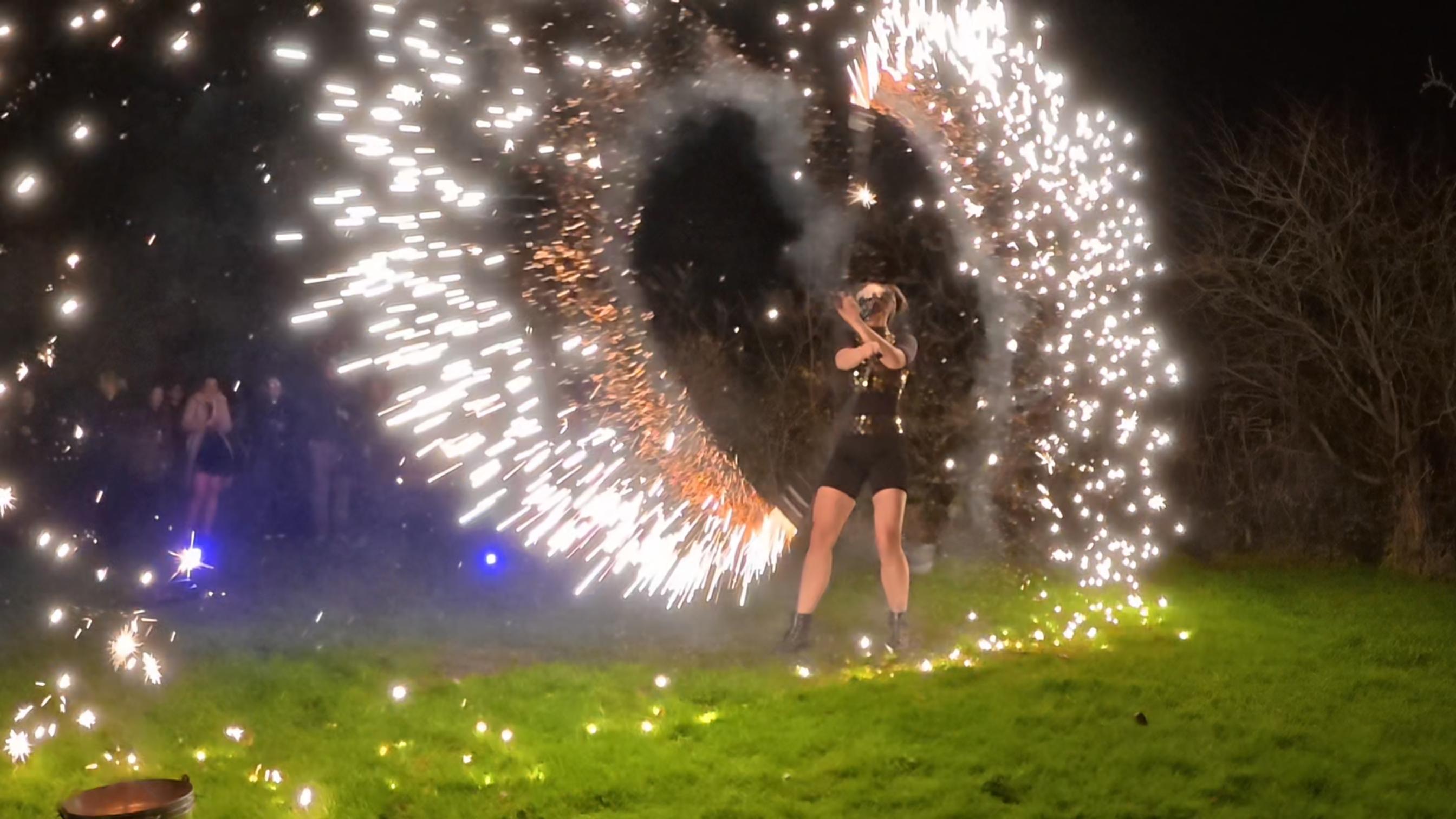 A performer dazzles at night, expertly spinning fire in a vibrant display, surrounded by spectators immersed in the magical atmosphere.