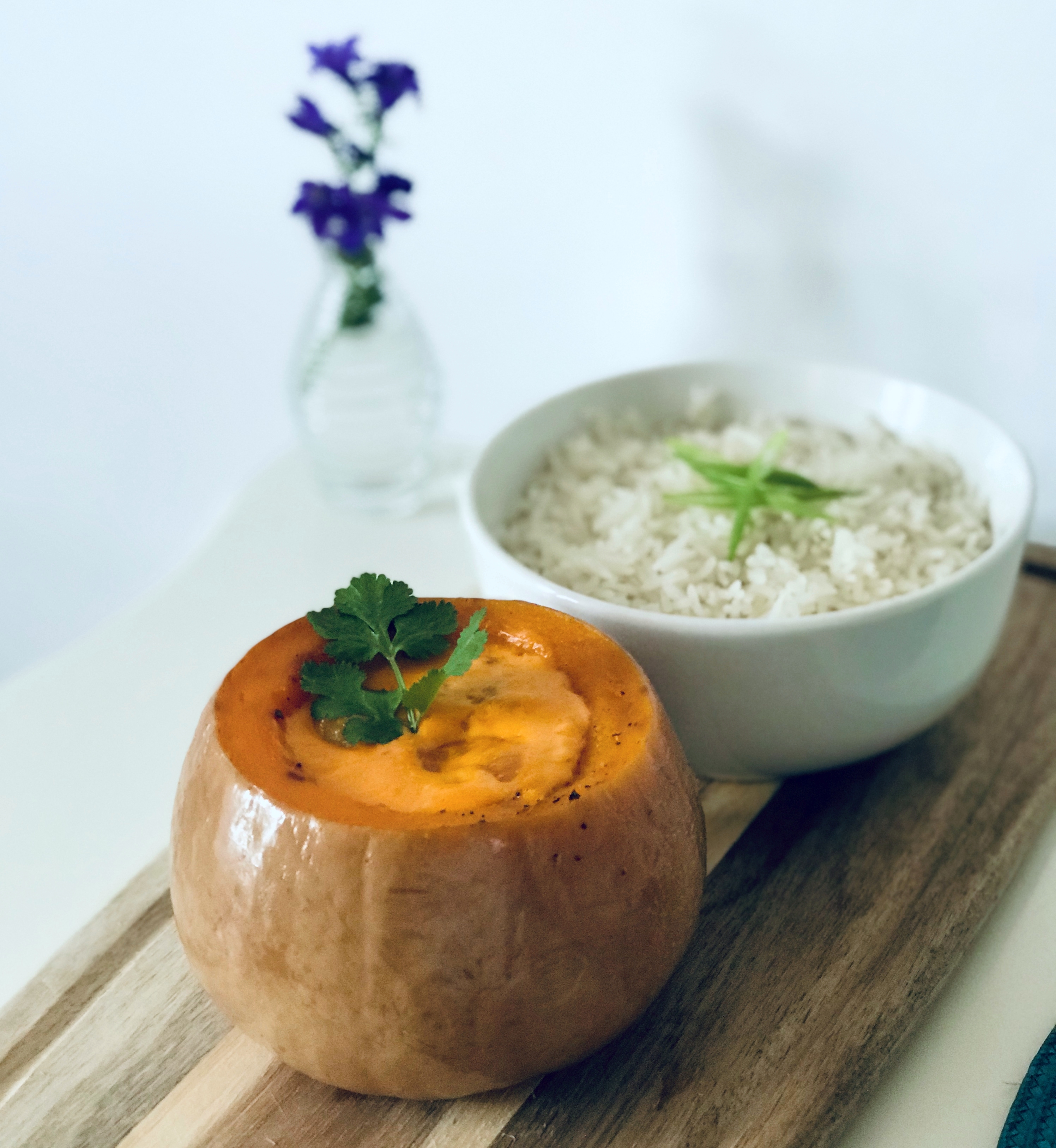 Catering-style plated squash and rice on a wooden board, garnished with cilantro, under bright minimalist daylight.
