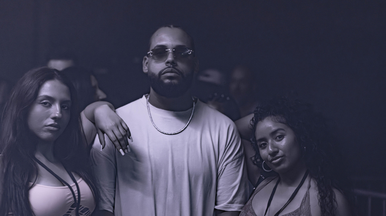 Moody nightclub crowd with three stylish guests under soft purple lighting, polished lenses and sleek streetwear, upscale event energy.