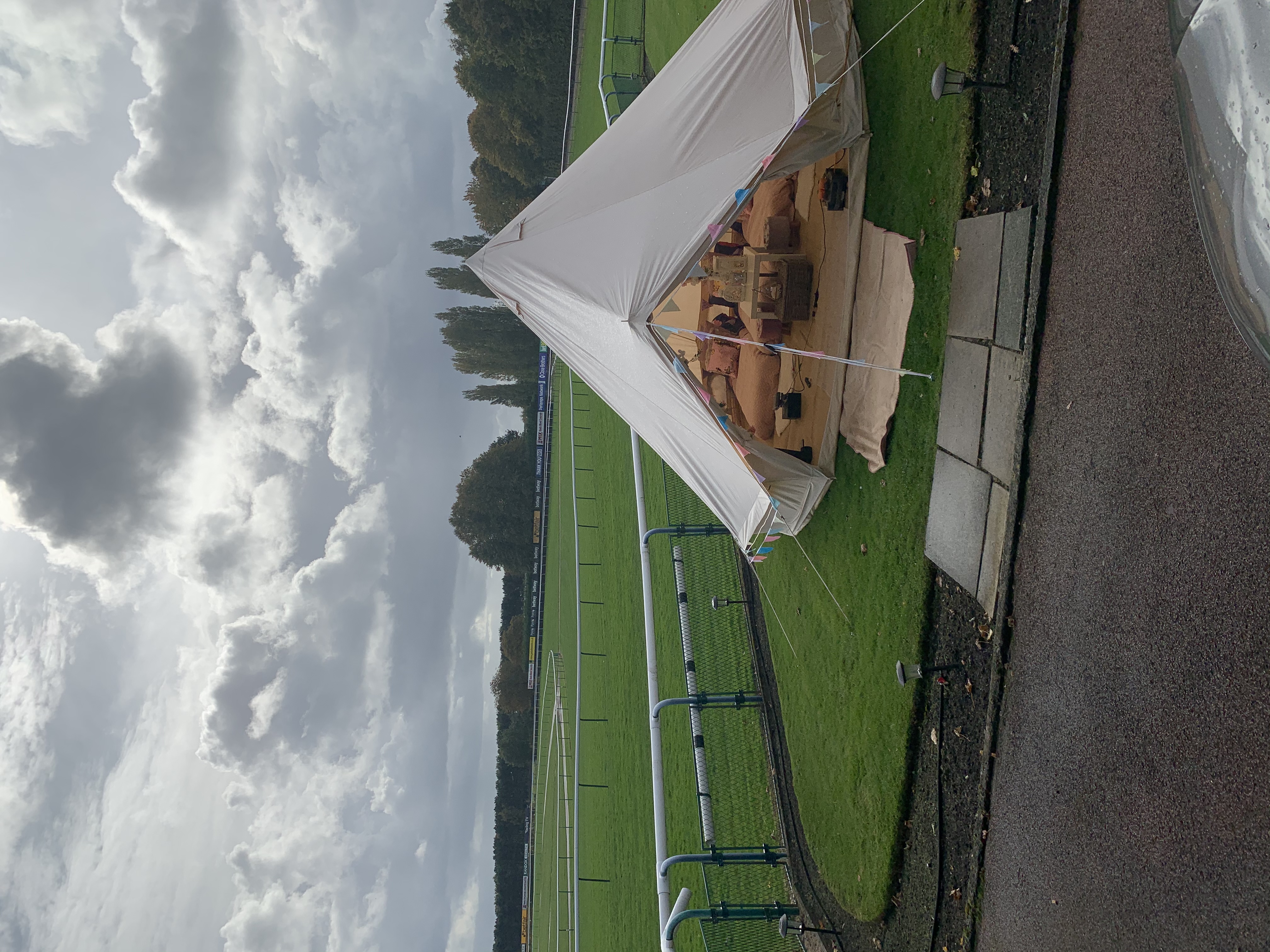 A cozy bell tent decoratively adorned with colorful bunting sits on lush green grass, with warm ambient lighting creating a welcoming vibe.