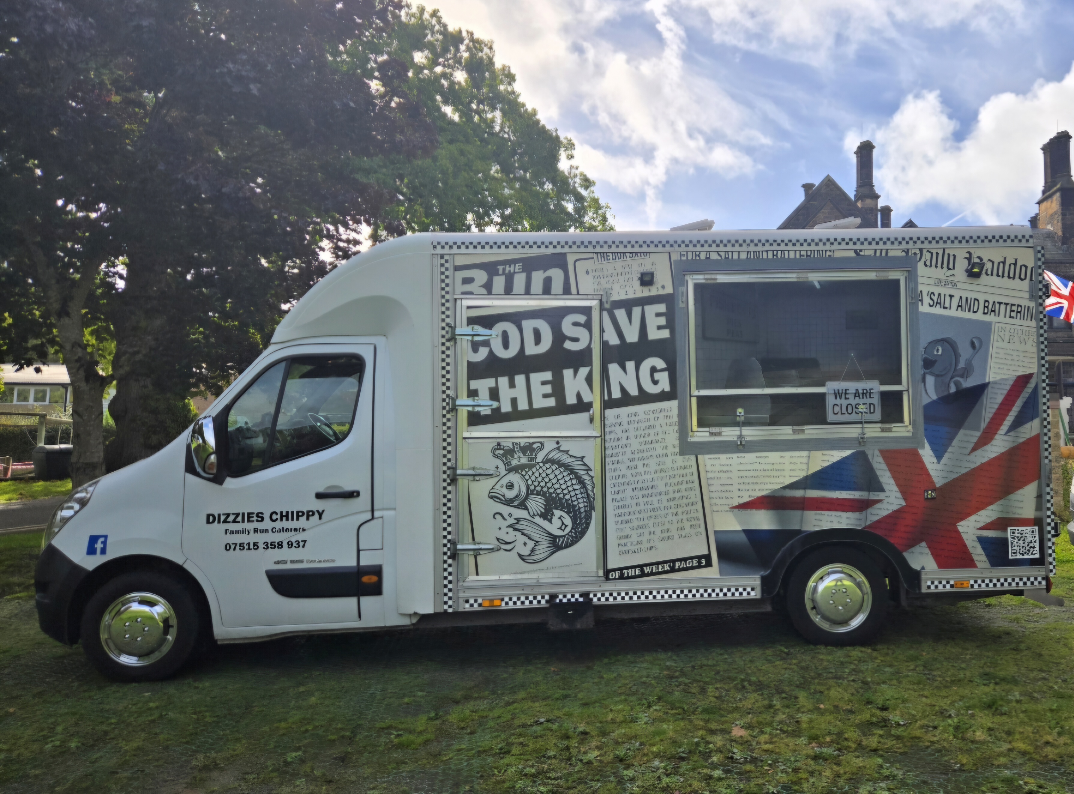 White chippy catering van with Union Jack graphics and “We Are Closed” sign, parked on grass under bright daylight.