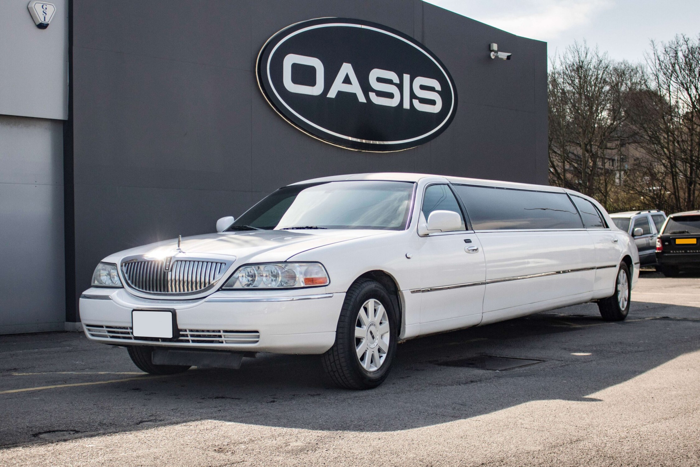 A gleaming white limousine parked against a sleek gray backdrop, showcasing modern elegance perfect for high-end events and luxury transportation.