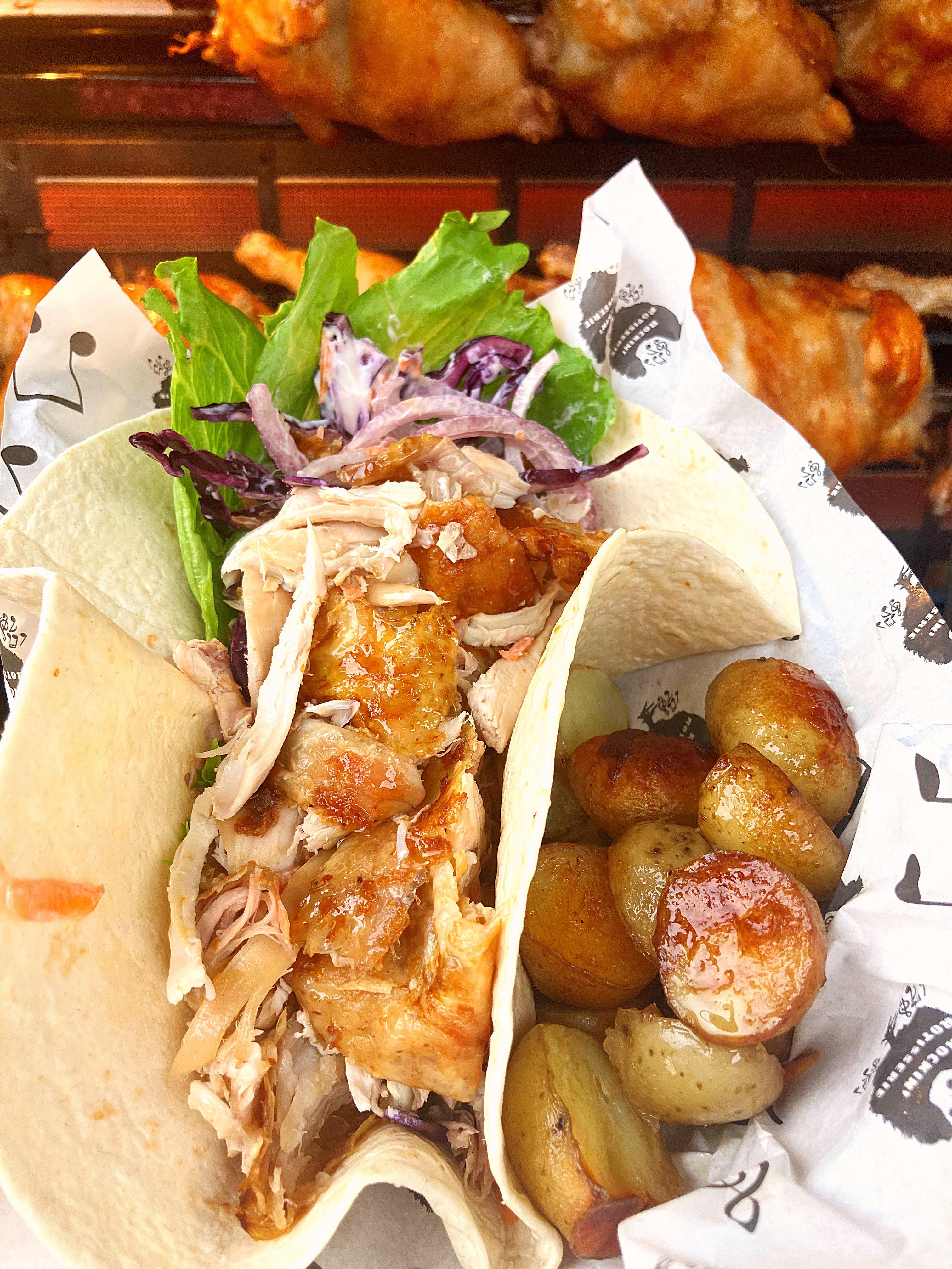 A fresh taco features shredded chicken, crispy lettuce, and purple cabbage, paired with golden roasted potatoes, wrapped in soft tortillas.