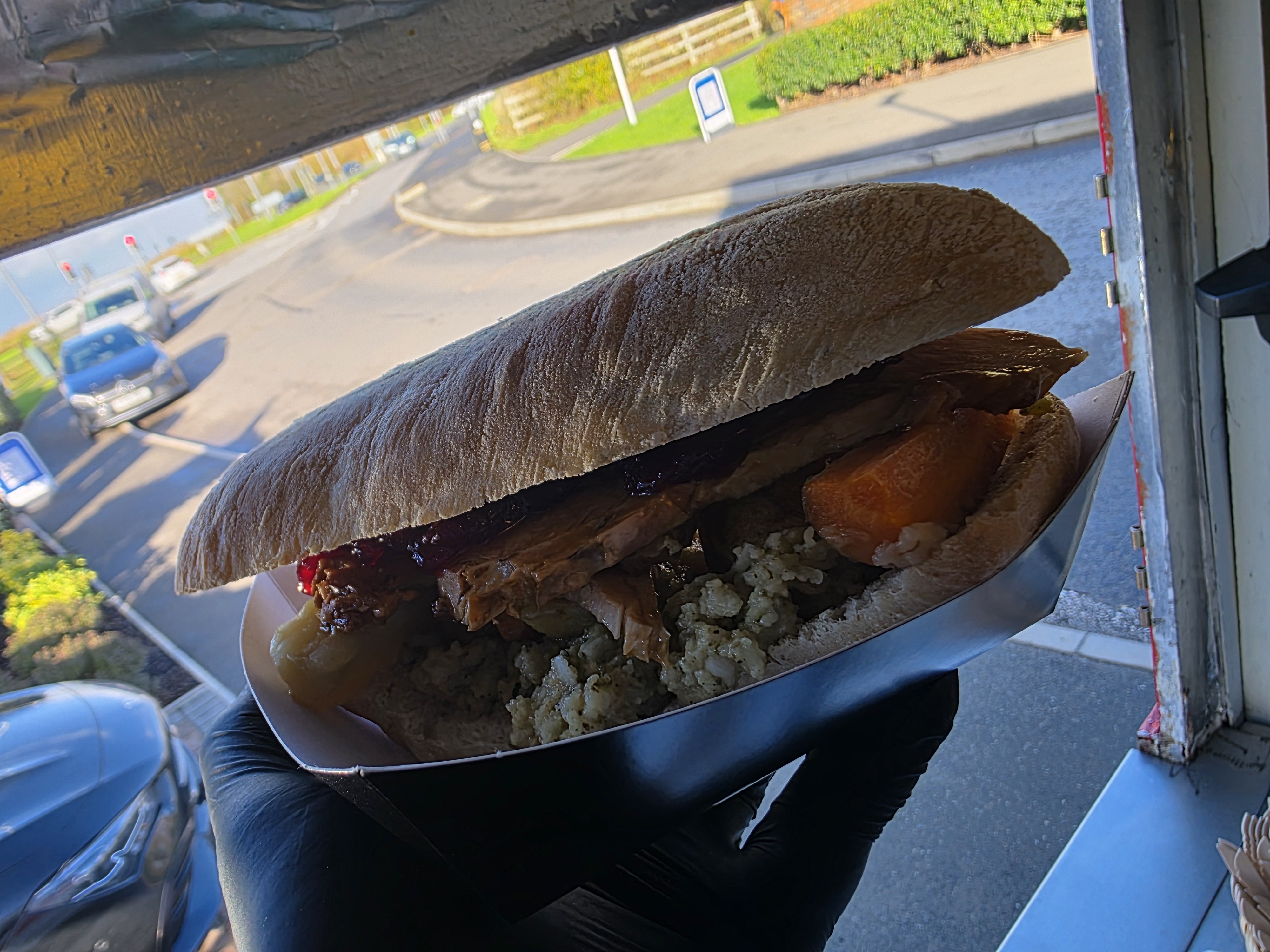 A hearty sandwich boasts tender pulled pork, rich barbecue sauce, and sweet roasted peppers, nestled in a rustic, flour-dusted bun.