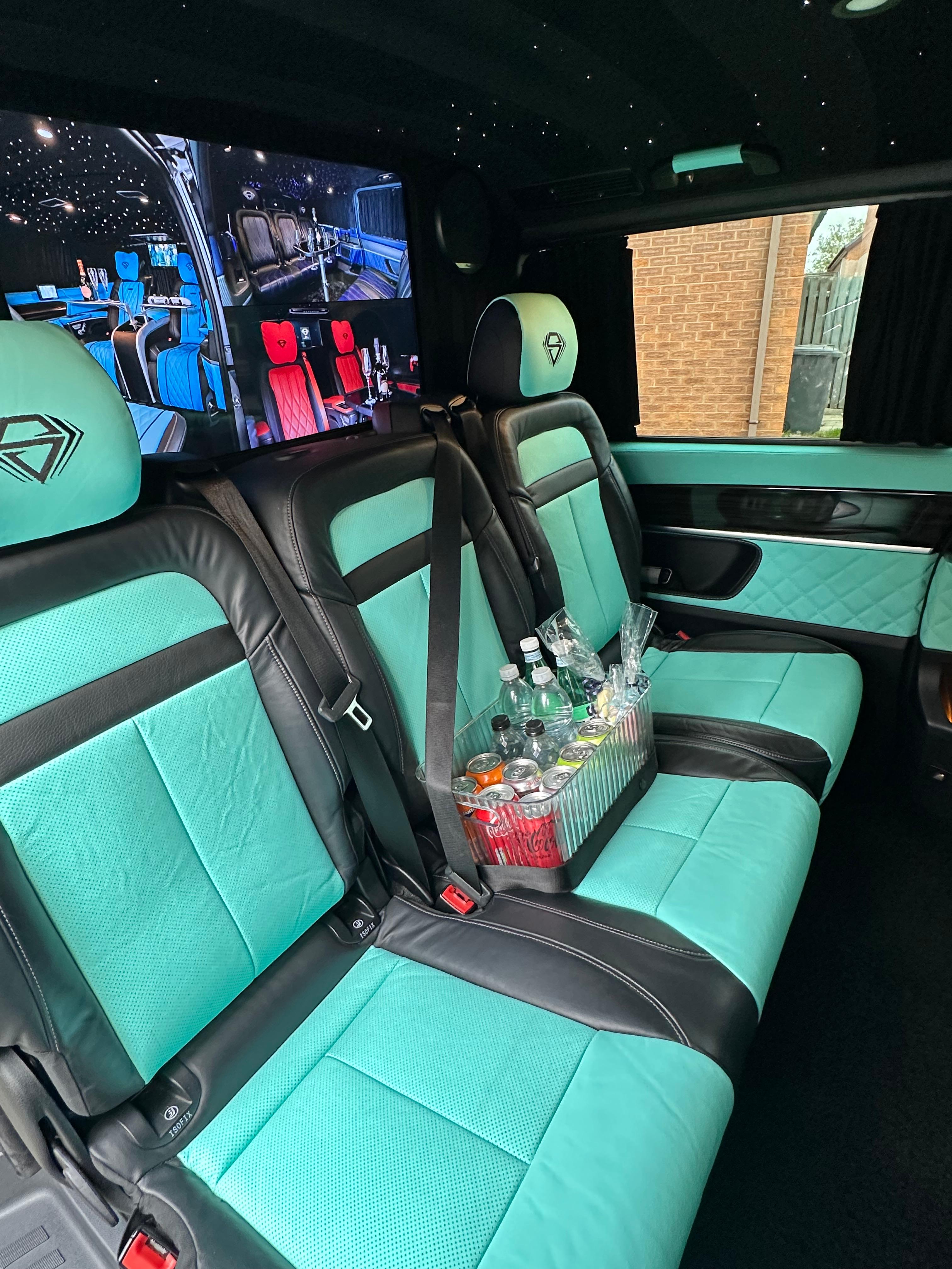 Luxurious black and aquamarine leather seating with polished accents, featuring a sleek drink holder filled with assorted drinks. The interior exudes an upscale vibe under soft ambient lighting.