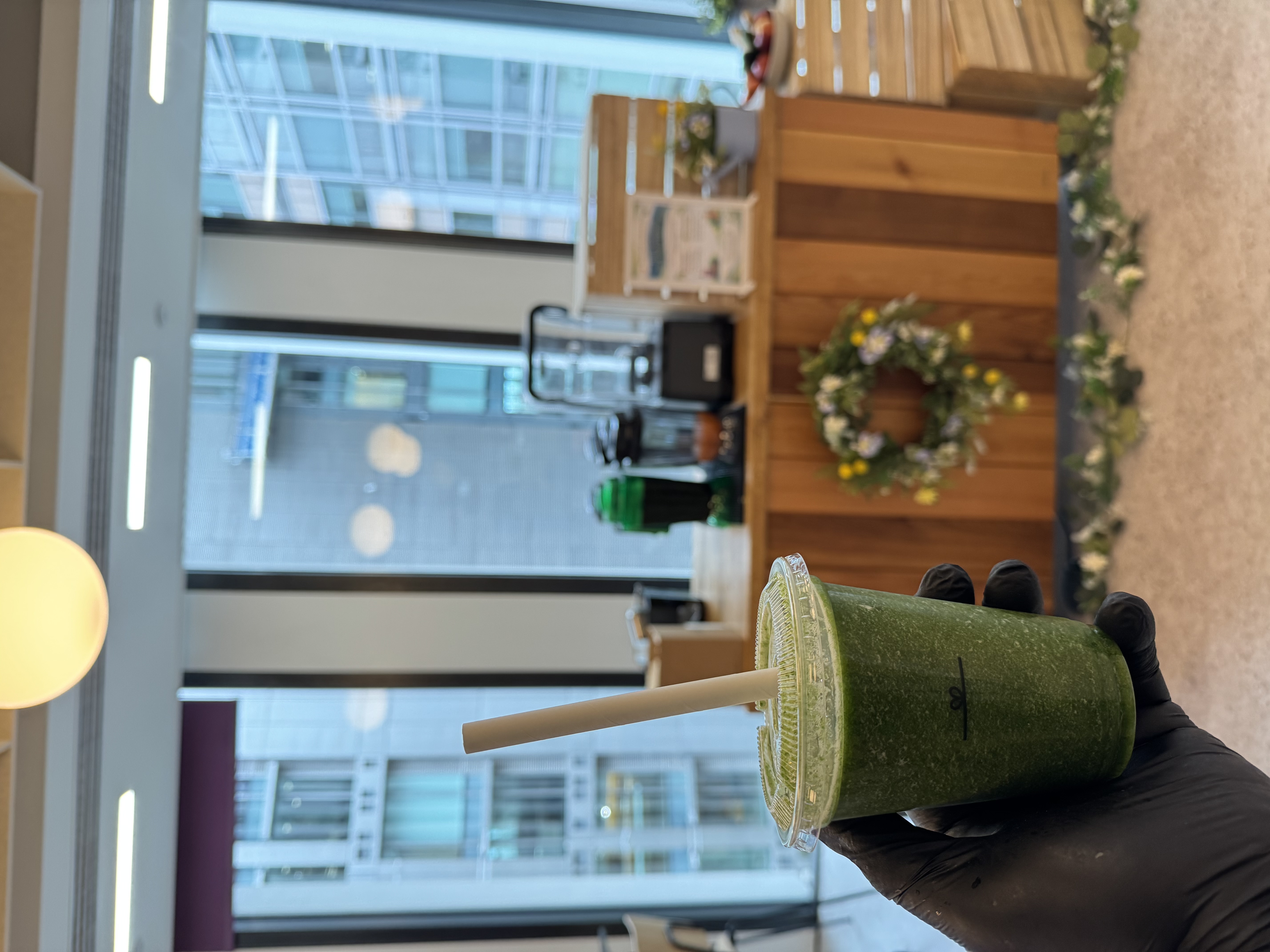 Three vibrant smoothies—strawberry, green kale, and mango—are arranged on a rustic wooden counter, reflecting fresh, healthy choices.