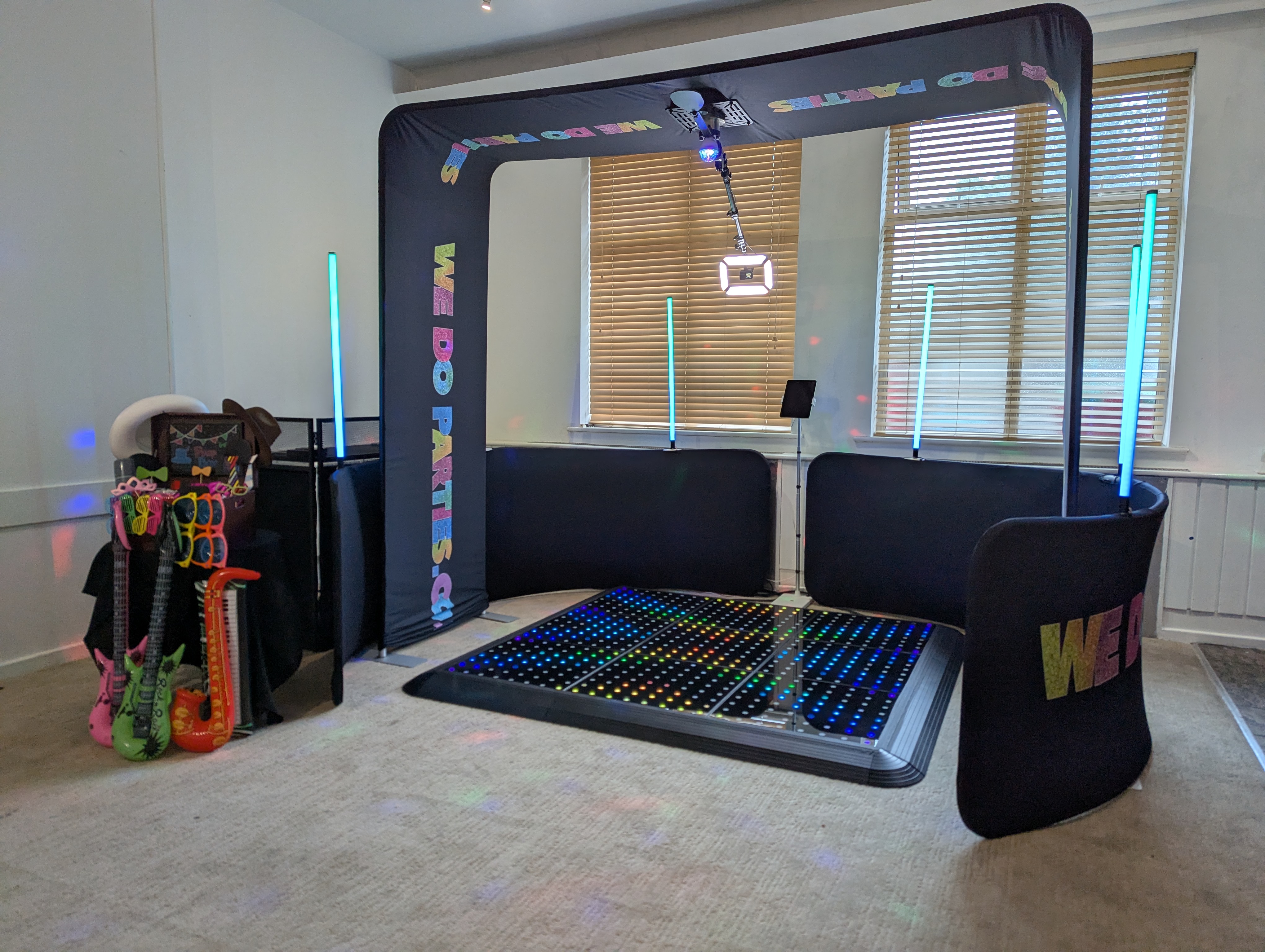 A vibrant party setup features a LED light dance floor under colorful beams, flanked by fun props, creating an energetic and inviting atmosphere.