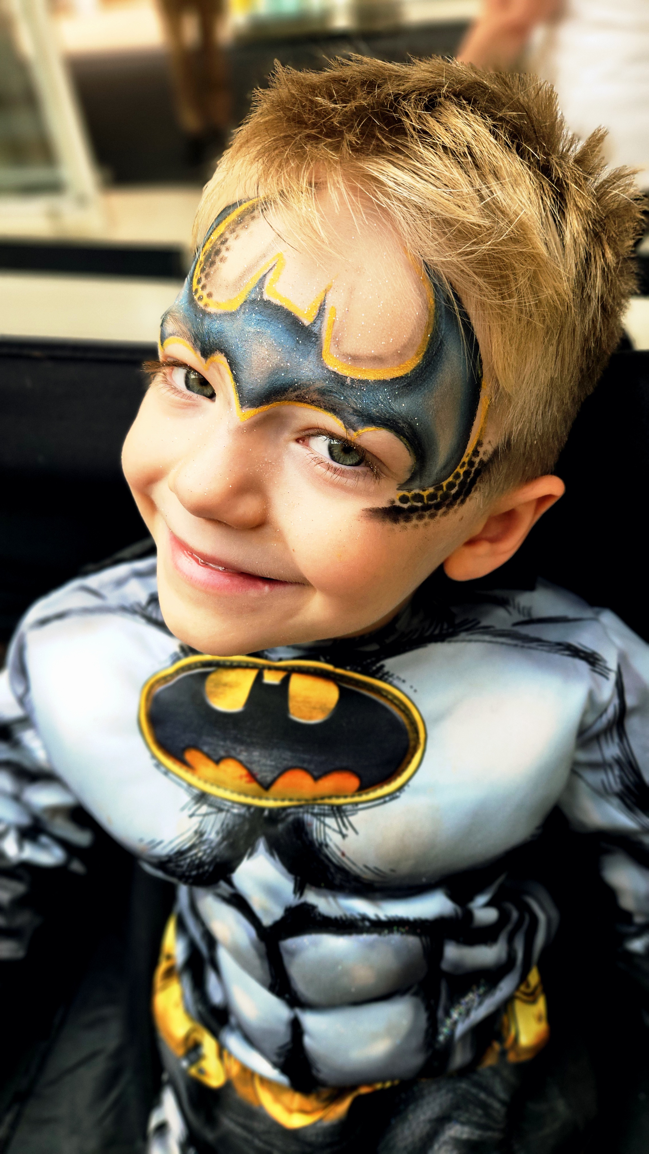 A joyful child displays vibrant face paint featuring bold colors, stars, and patterns, showcasing artistic flair and creativity.