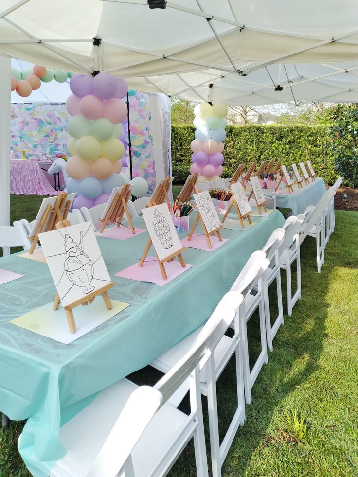 A vibrant outdoor setup features pastel balloons and mint table covers, with easels displaying ice cream coloring sheets, creating a playful atmosphere.