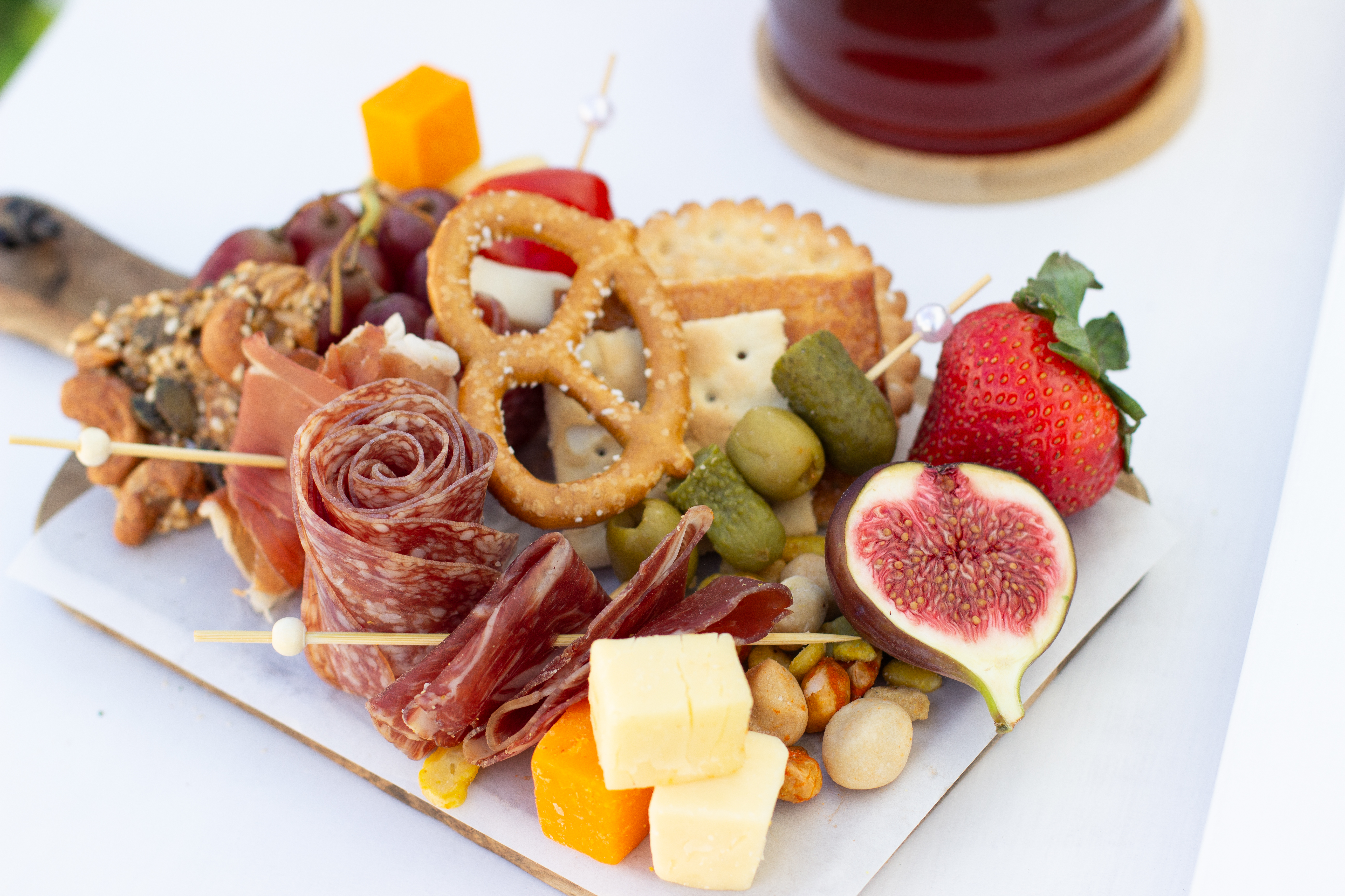 A vibrant charcuterie board features prosciutto, salami, and cheddar cubes alongside fresh strawberries and figs, all on a wooden platter.