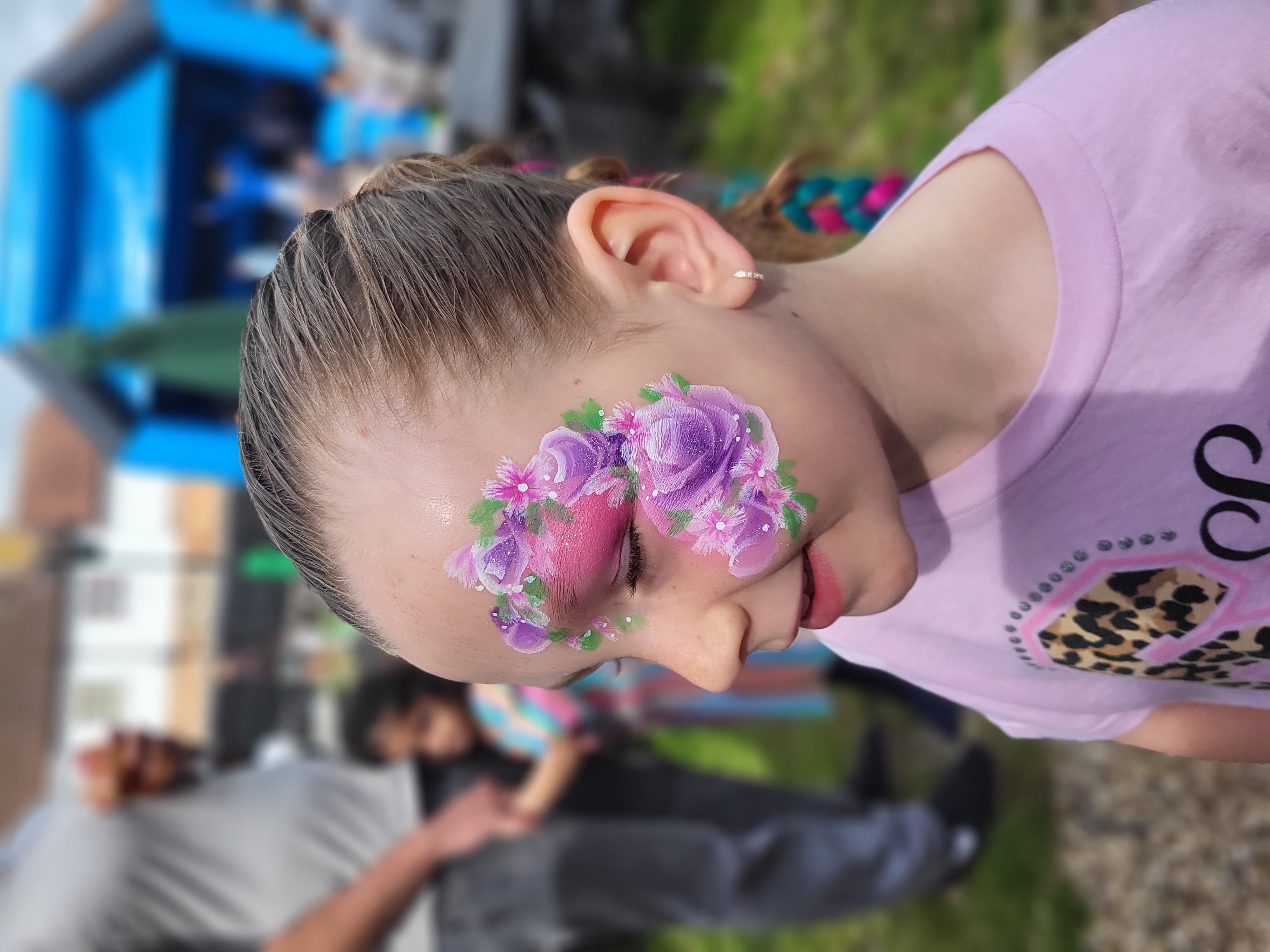 A child with vibrant sugar skull face paint features soft pastel hues of pink and green, exuding a festive yet cheerful atmosphere.