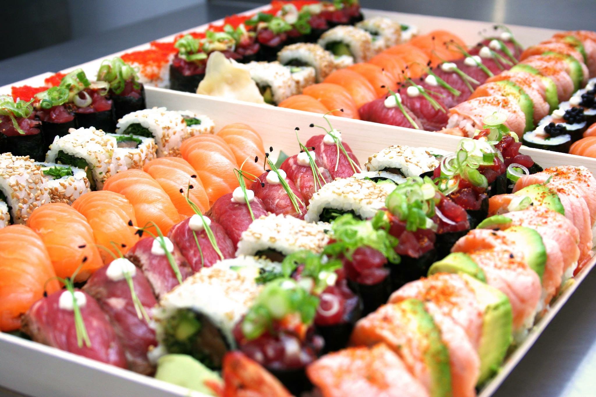 A vibrant sushi platter features neatly arranged salmon, avocado rolls, and colorful toppings, under soft, inviting lighting for a cozy dining experience.