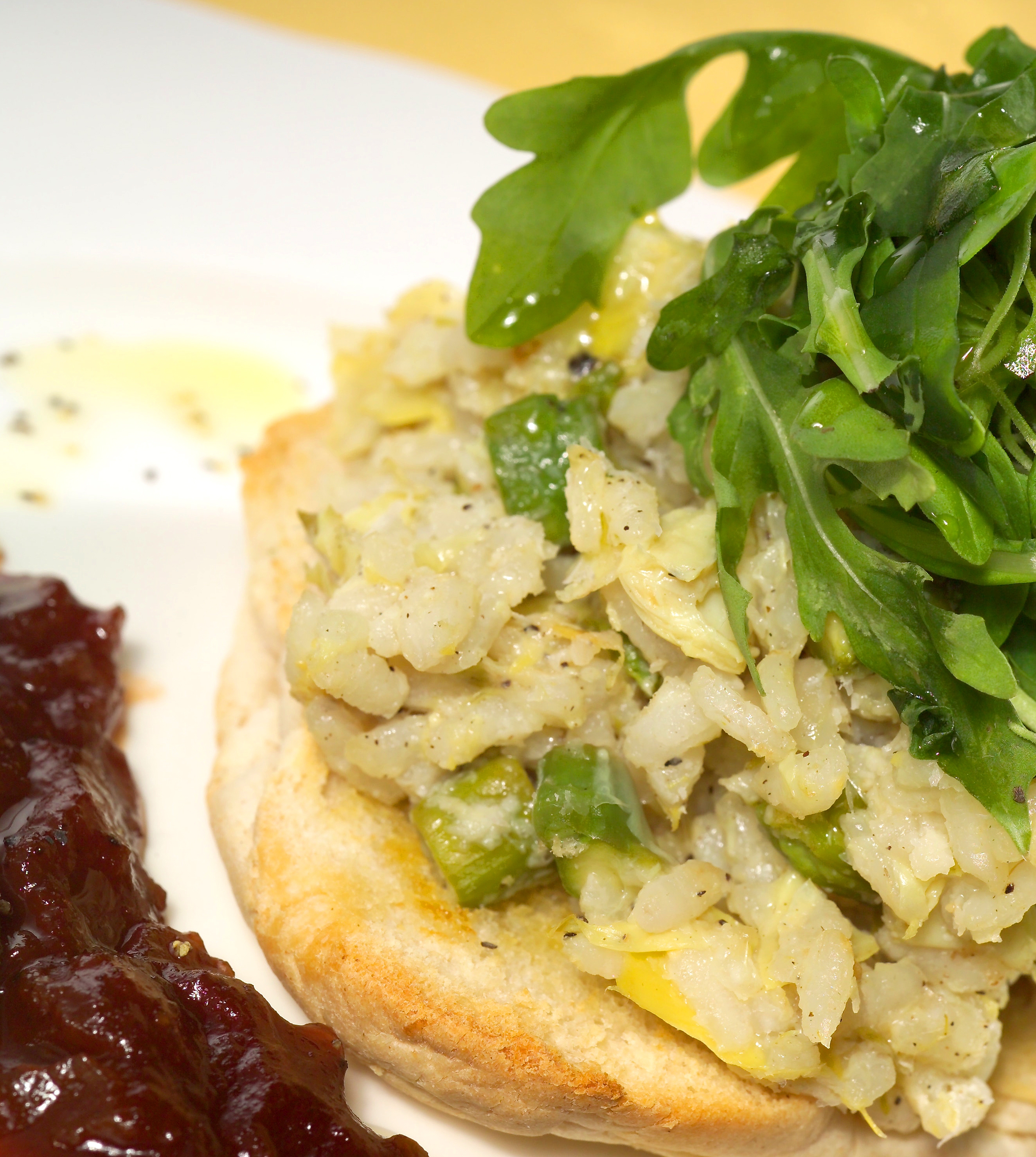 A crispy bread base topped with green veggies and arugula, accompanied by rich, dark berry sauce, captures a fresh, gourmet vibe.