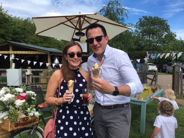 A sunny outdoor setting showcases a couple enjoying artisanal ice cream cones, vibrant drinks, and festive bunting, exuding a cheerful vibe.