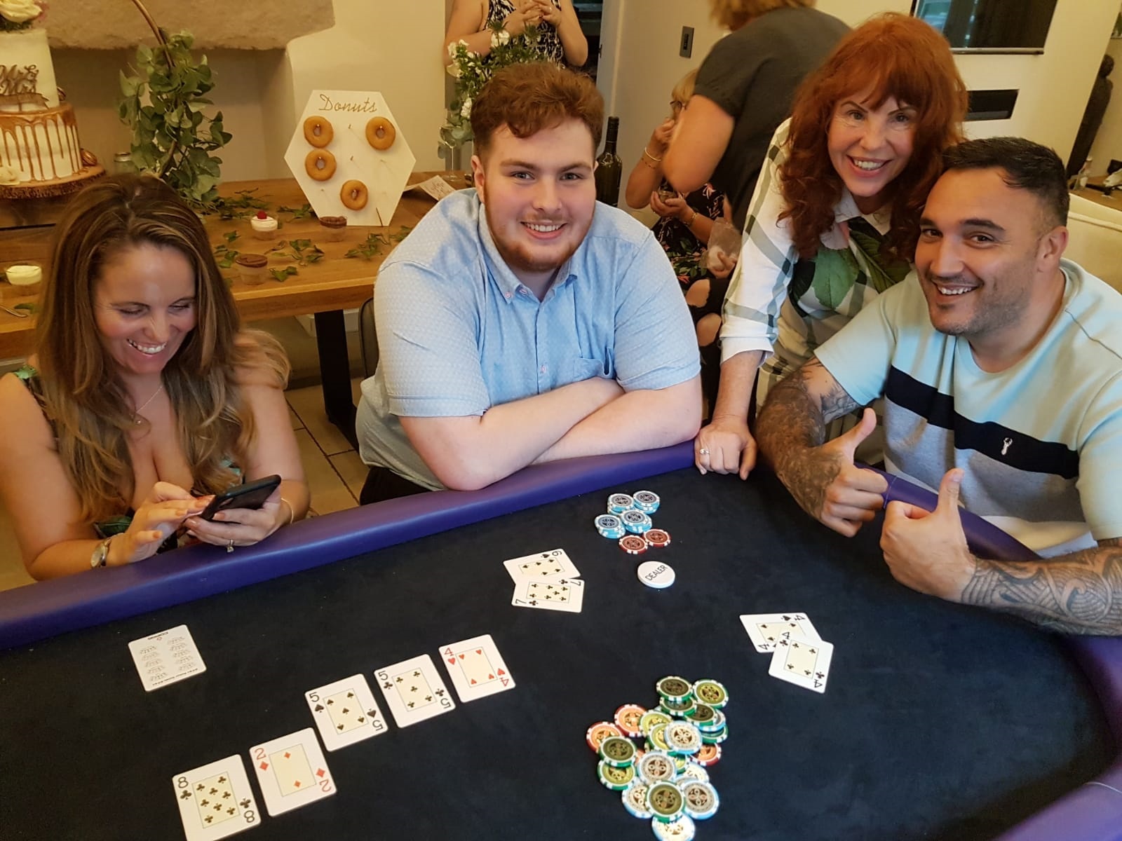 A lively gathering features four people around a poker table with colorful chips, enjoying a fun atmosphere and snacks in the background.